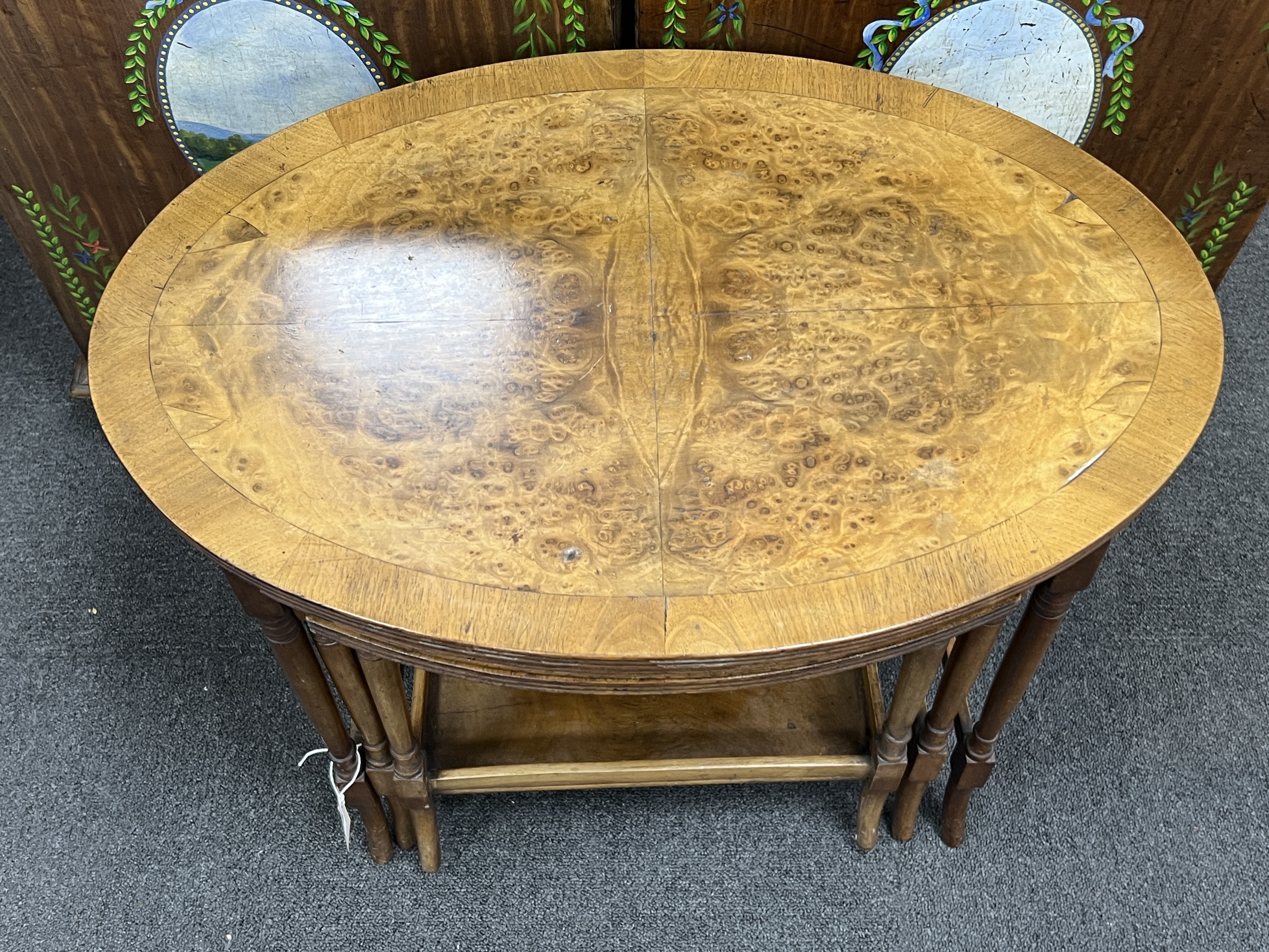 A nest of three oval burr walnut teak tea tables, width 61cm, depth 41cm, height 52cm
